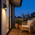 Bell Shade Aluminium Outdoor Wall Light on a rendered wall beside a timber deck at dusk