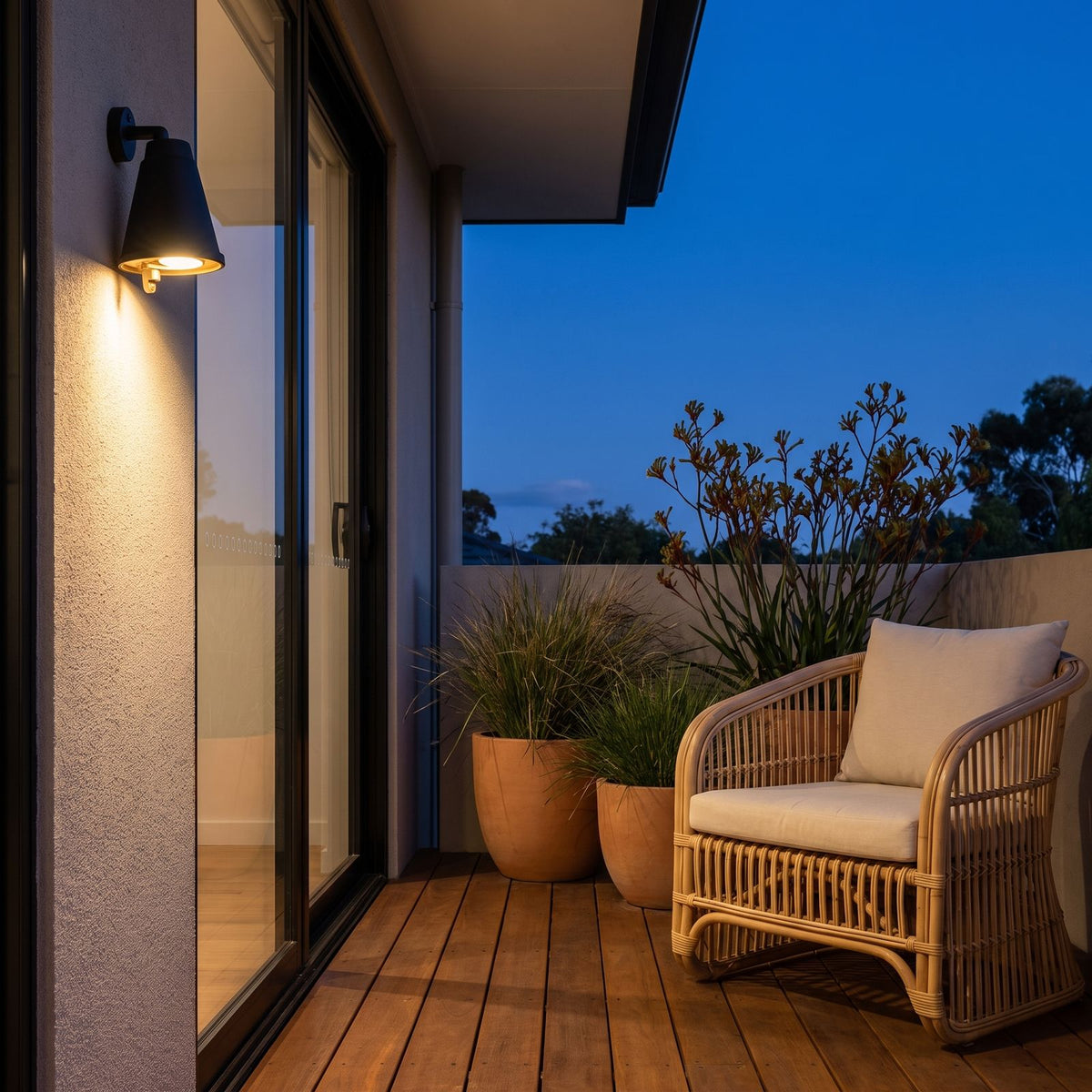 Bell Shade Aluminium Outdoor Wall Light on a rendered wall beside a timber deck at dusk