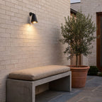 Bell Shade Aluminium Outdoor Wall Light above a concrete bench on a brick courtyard wall