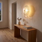 Bent Rod Round Glass Wall Light in a hallway above a timber console