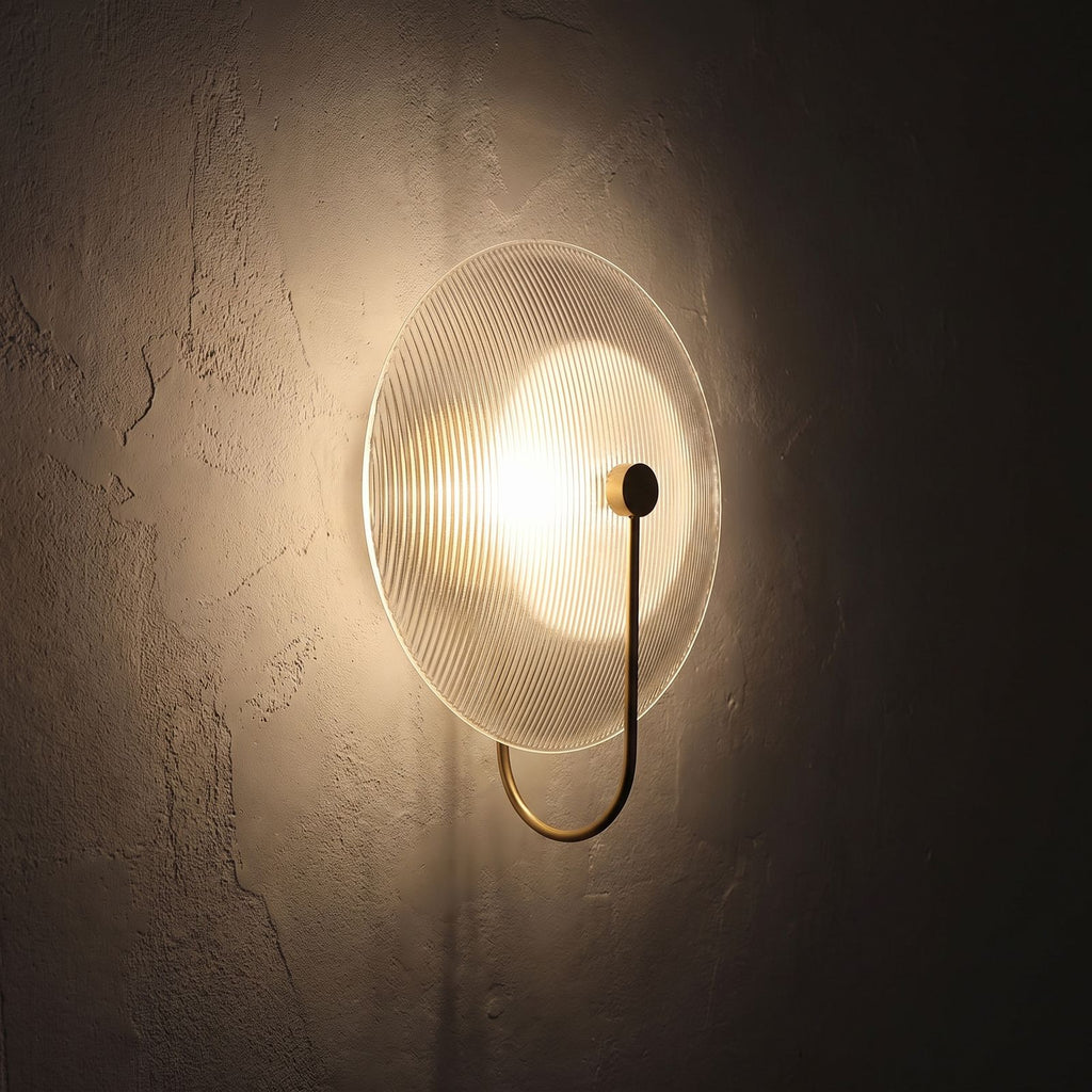 Bent Rod Round Glass Wall Light glowing on a plaster wall at night