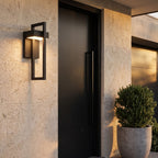 Black Frame Outdoor Wall Sconce beside a front door on a limestone wall