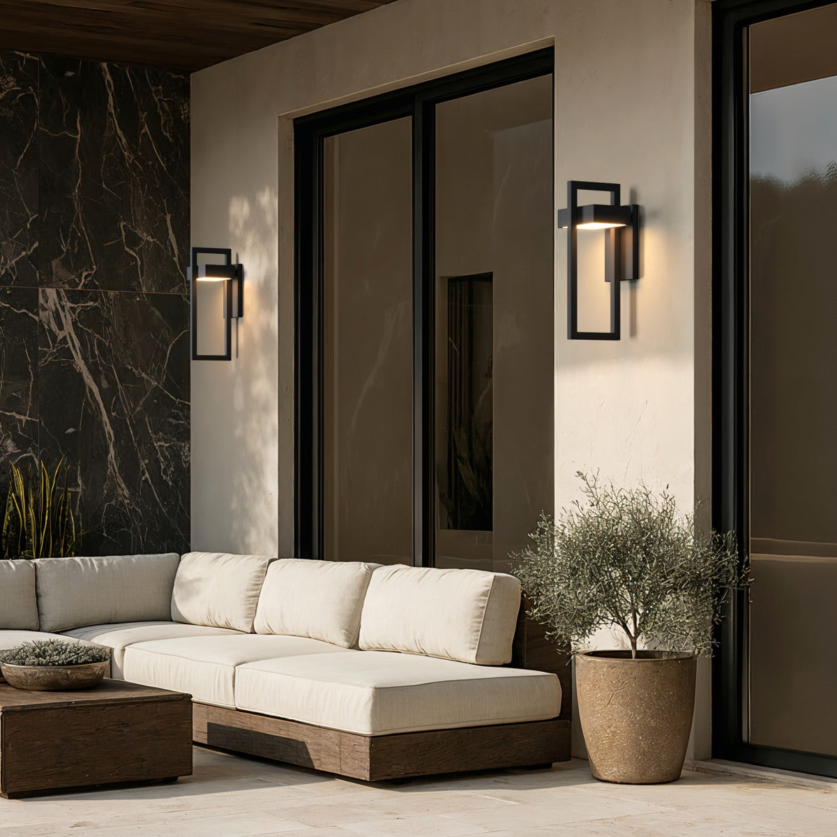 Black frame wall sconce above an outdoor sofa on a patio