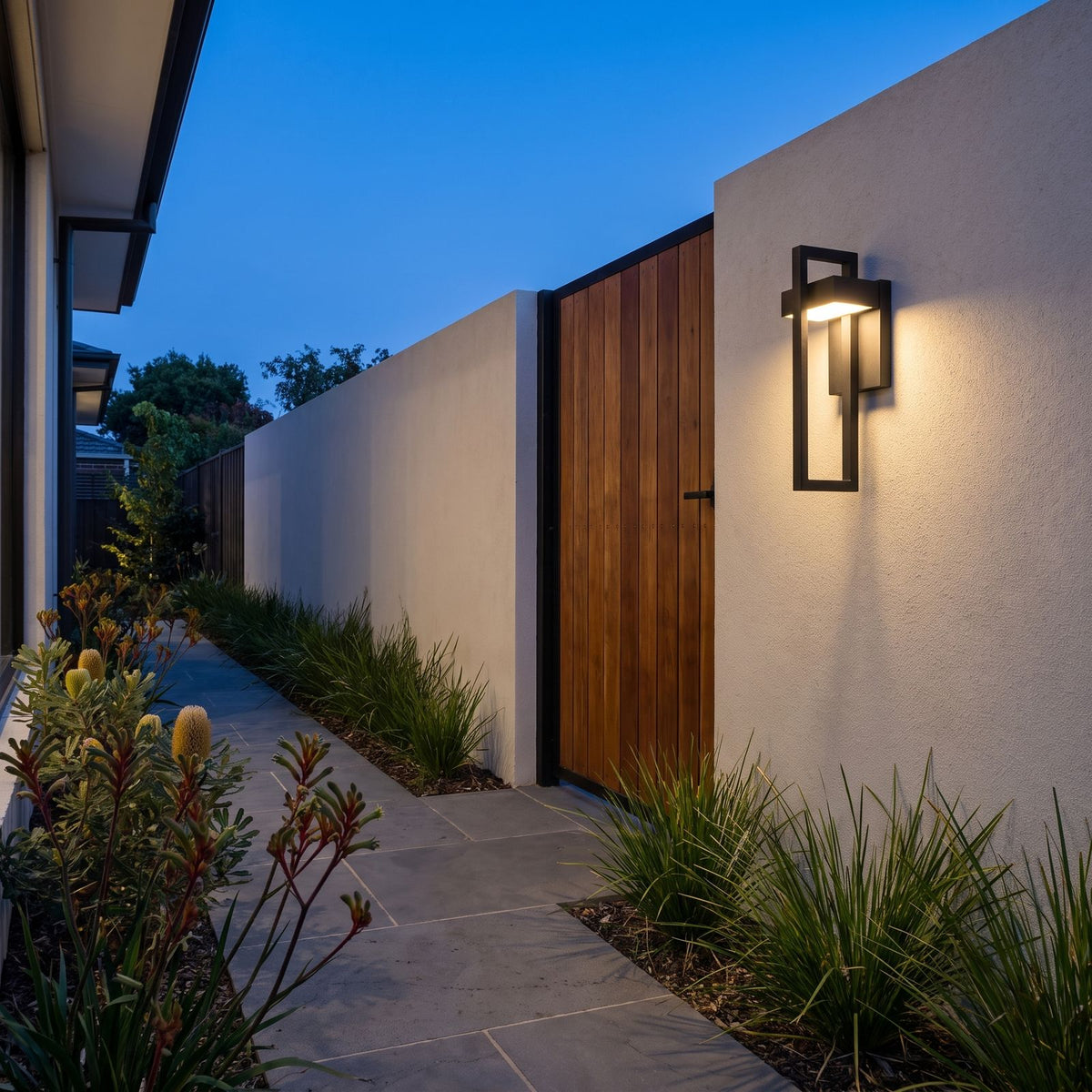 Black Frame Outdoor Wall Sconce on a garden path wall at dusk