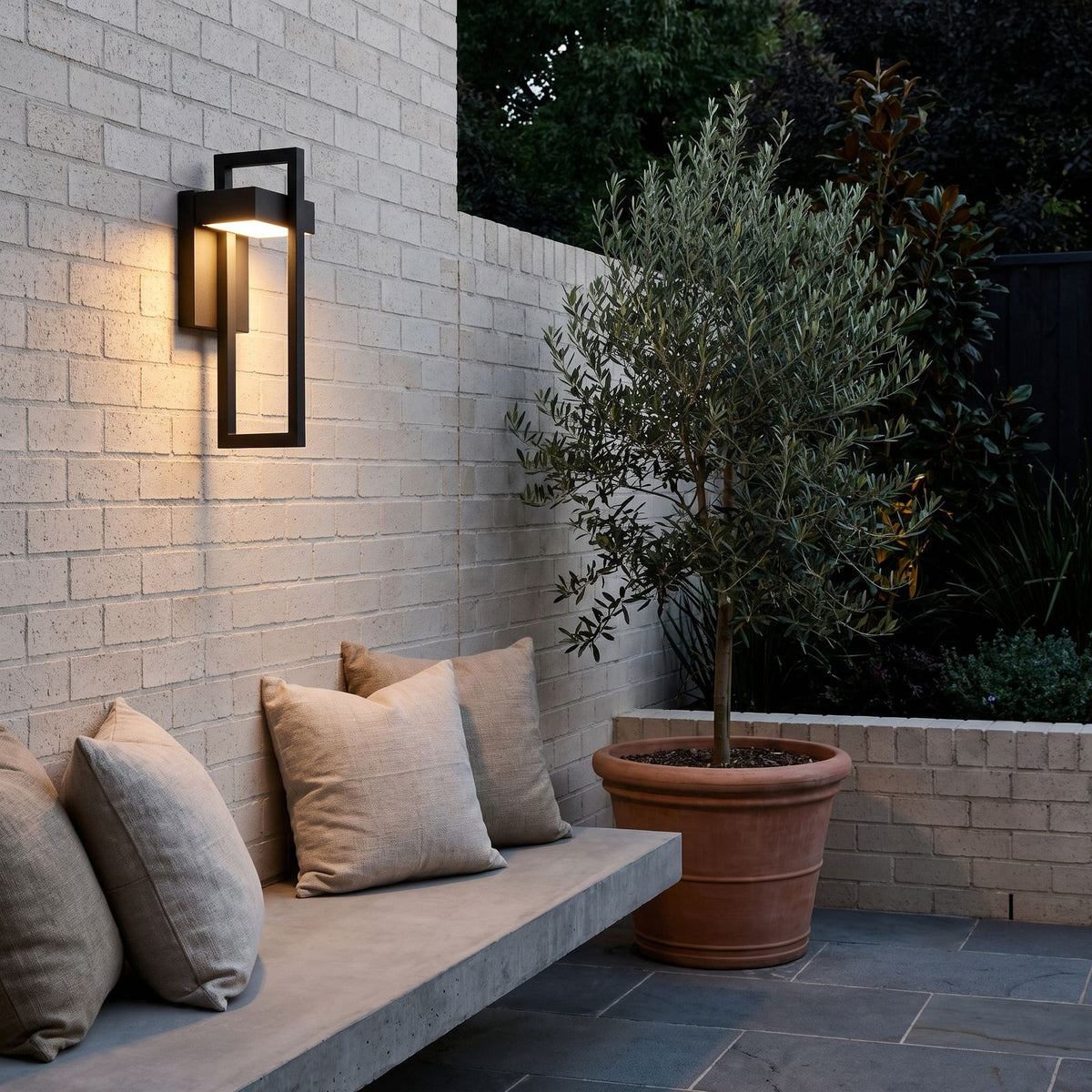 Black Frame Outdoor Wall Sconce above a concrete bench in a courtyard