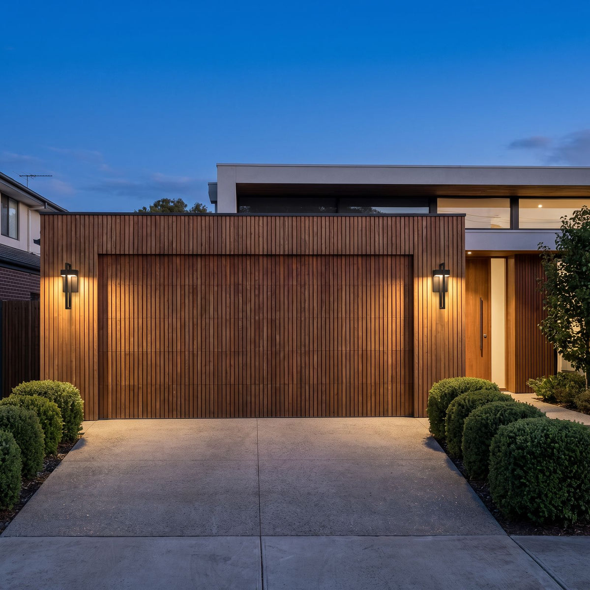 A pair of Black Frame Outdoor Wall Sconces either side of a timber garage door