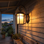 Black Iron and Amber Glass Outdoor Wall Light on a porch wall at dusk