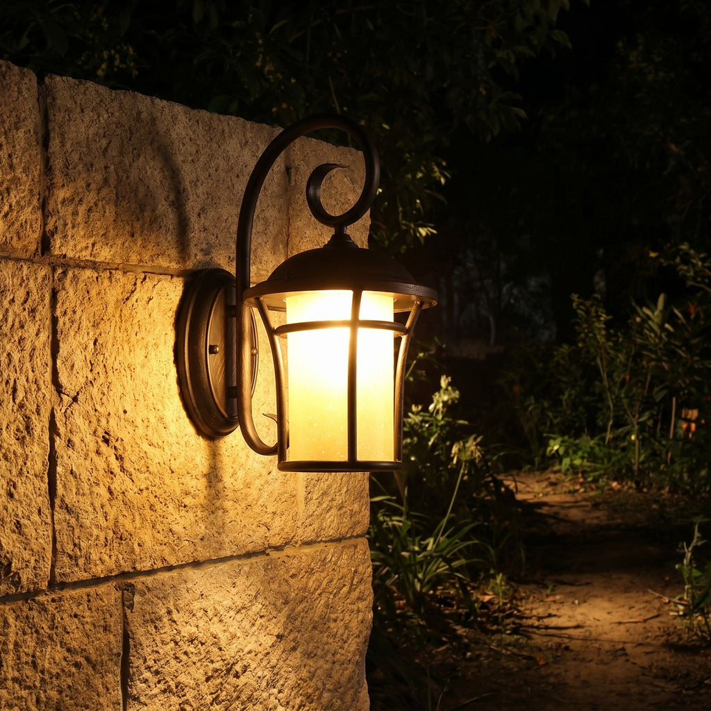 Black Iron and Amber Glass Outdoor Wall Light glowing on a garden wall at night