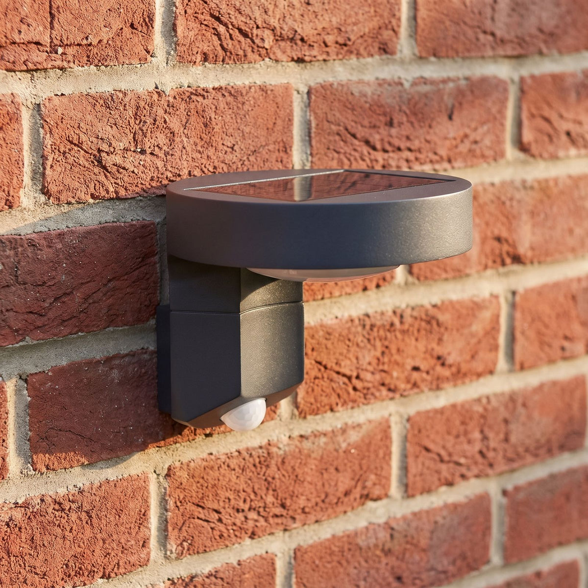 Black Metal and Acrylic Solar Sensor Wall Light, close view at 45 degrees on a stone wall