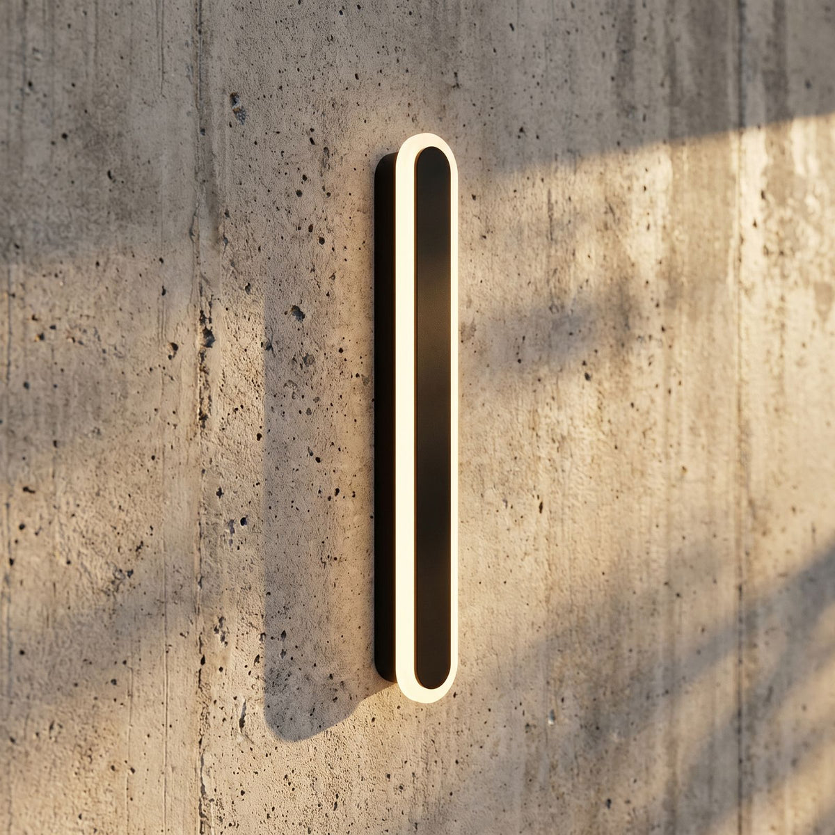 Black Oval Linear LED Outdoor Wall Light, close view at 45 degrees on a stone wall