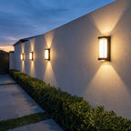 Four Black Up Down Outdoor Wall Lights along a boundary wall at blue hour