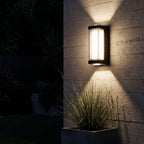 Black Up Down Outdoor Wall Light lighting a concrete wall at night