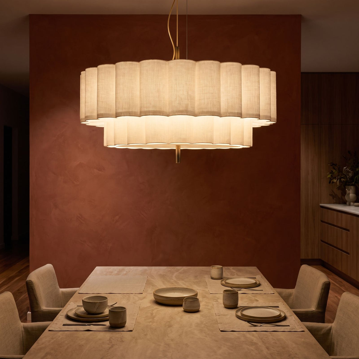Boho Knitted Fabric Ripple Pendant Light glowing against a plaster wall at night