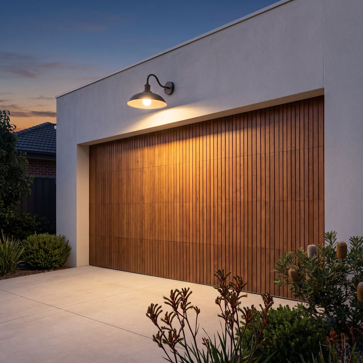 Bowl Shade Gooseneck Outdoor Wall Light above a timber garage door at dusk