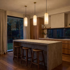 A row of three Brass and Alabaster Capsule Pendant Lights over a stone kitchen island