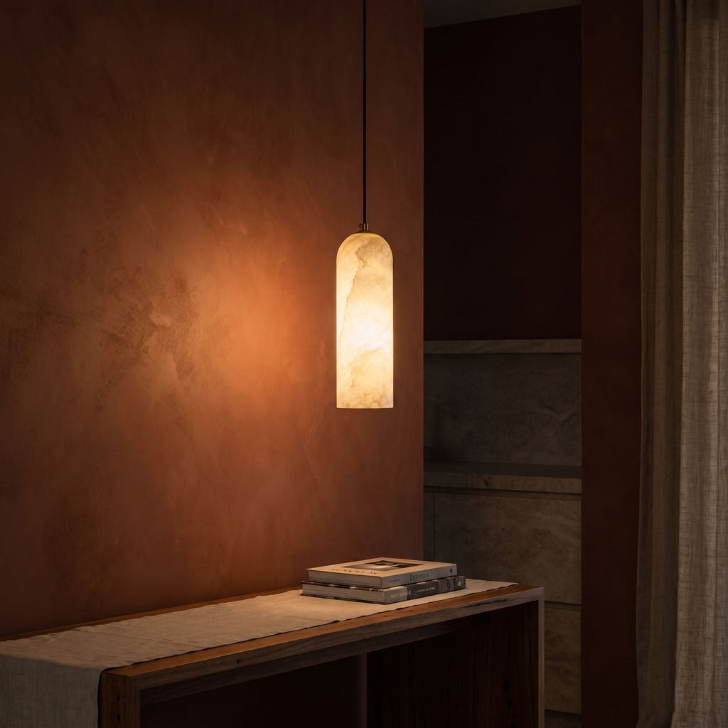 Brass and Alabaster Capsule Pendant Light glowing against a plaster wall at night
