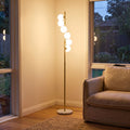 Brass Finish 6-Light Opal Glass Globe Floor Lamp beside an armchair in a living room corner