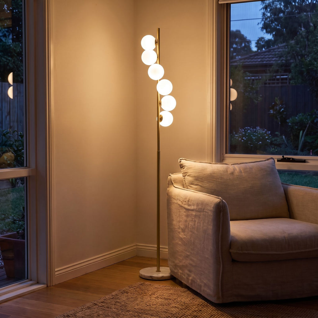 Brass finish opal glass globe floor lamp behind a sofa at night