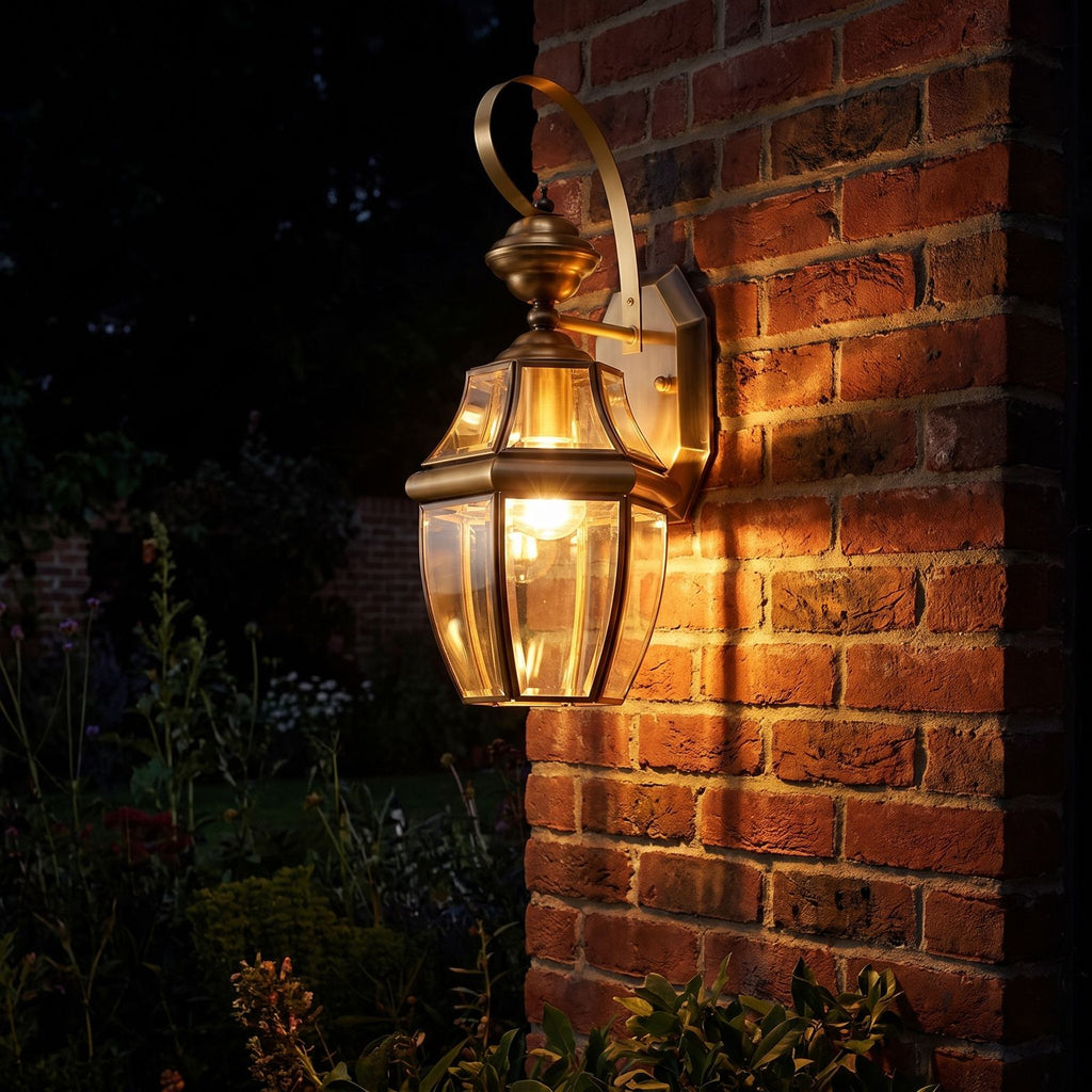 Brass Lantern Outdoor Wall Light glowing on a garden wall at night