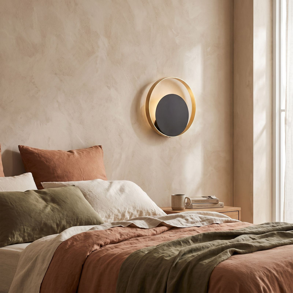 Brass Ring and Black Disc Wall Light on a bedroom wall beside the bed