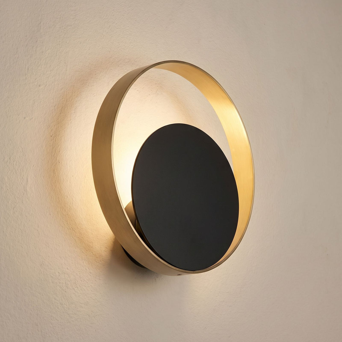 Brass Ring and Black Disc Wall Light, close view at 45 degrees on a plaster wall