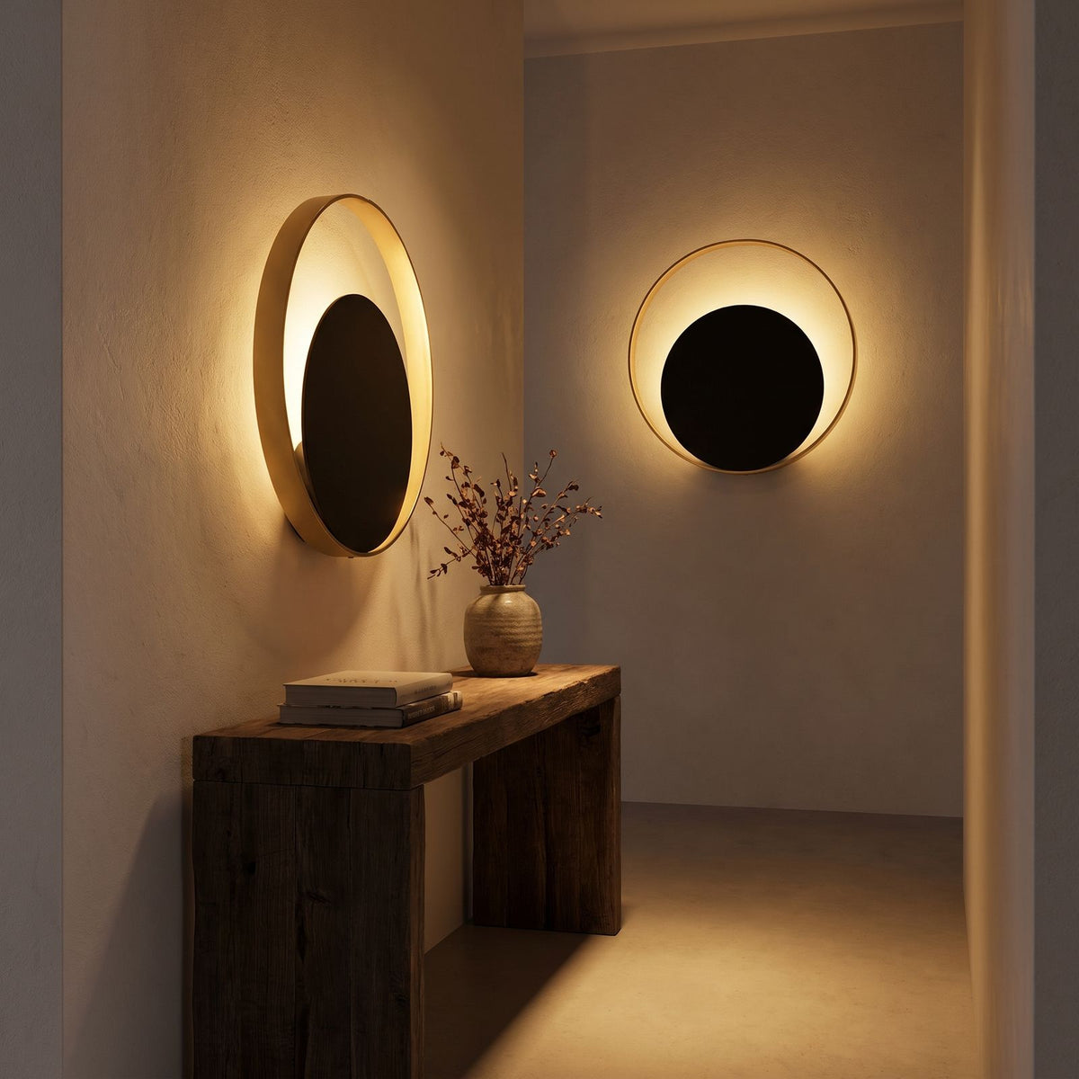 Brass Ring and Black Disc Wall Light in a hallway above a timber console