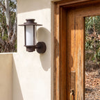 Brown Iron and Acrylic Lantern Outdoor Wall Light beside a timber front door
