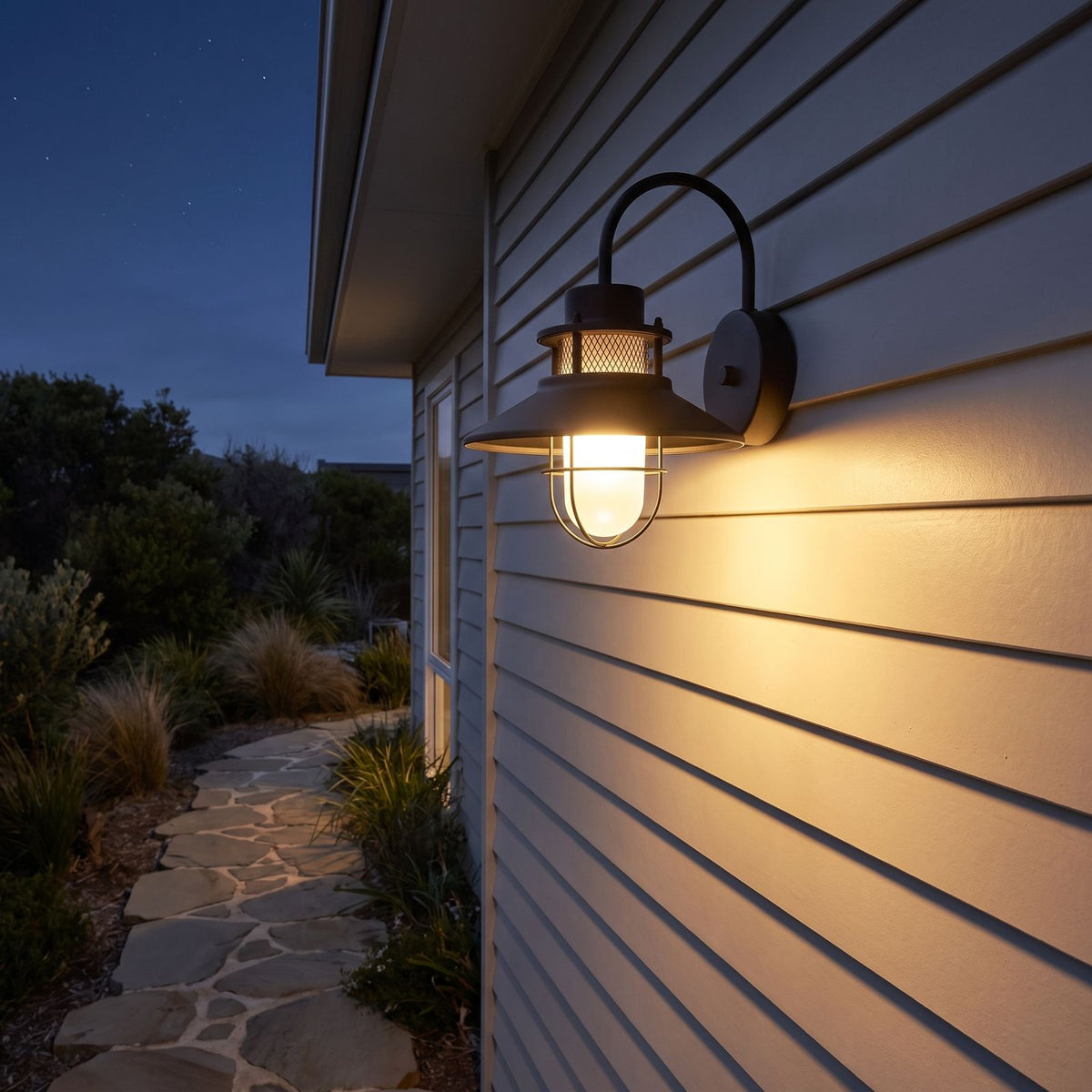 Caged frosted glass gooseneck outdoor wall light along a side passage at night