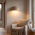 Stone half dome LED wall light above an armchair in a reading corner