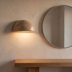 Stone half dome LED wall light beside a round mirror in an entry hall