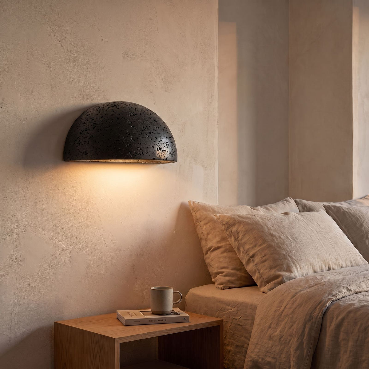 Carved Stone Half Dome LED Wall Light in black beside a bed