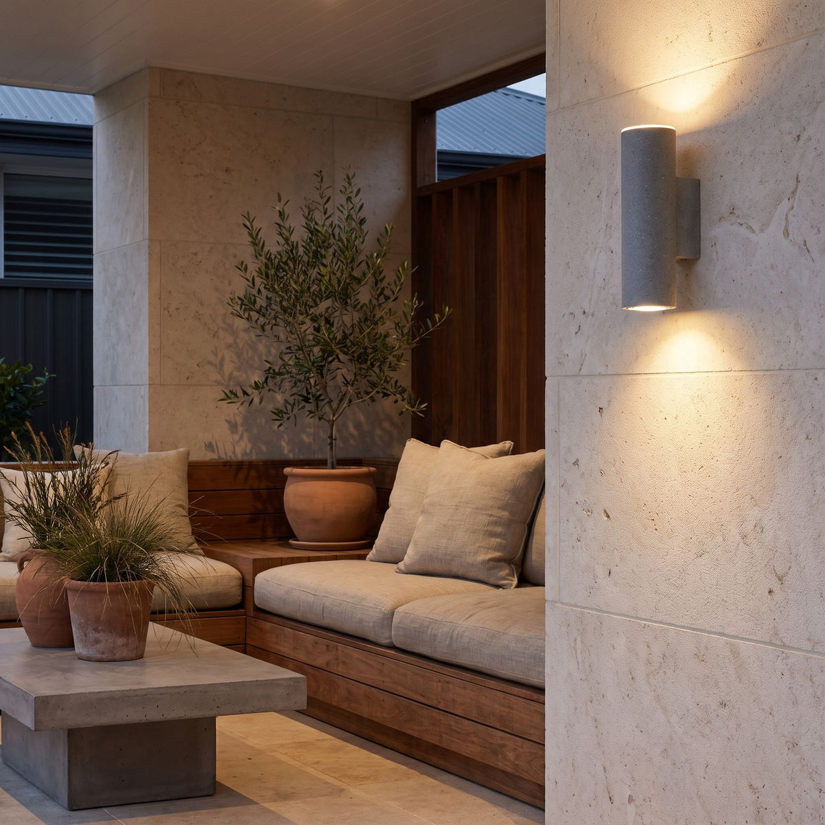 Cement and Acrylic Outdoor Wall Light on a limestone wall in a covered outdoor lounge