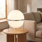 Chrome ring acrylic globe table lamp on a side table beside a sofa in daylight