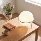 Chrome ring acrylic globe table lamp on a home office desk in daylight