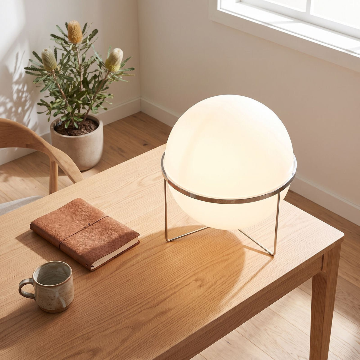 Chrome ring acrylic globe table lamp on a home office desk in daylight
