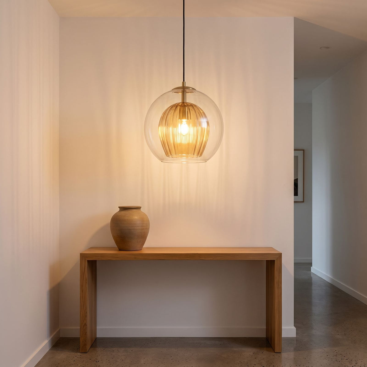 Clear and amber glass globe pendant light above an entry hall console