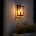 Clear Glass Lantern Outdoor Wall Light on a concrete wall at night