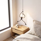 Climbing figure iron pendant light over a bedside table in daylight