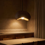 Coffee Brown Textured Resin Cloud Pendant Light glowing against a plaster wall at night