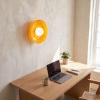 Coloured glass dish wall and ceiling light above a home office desk in daylight