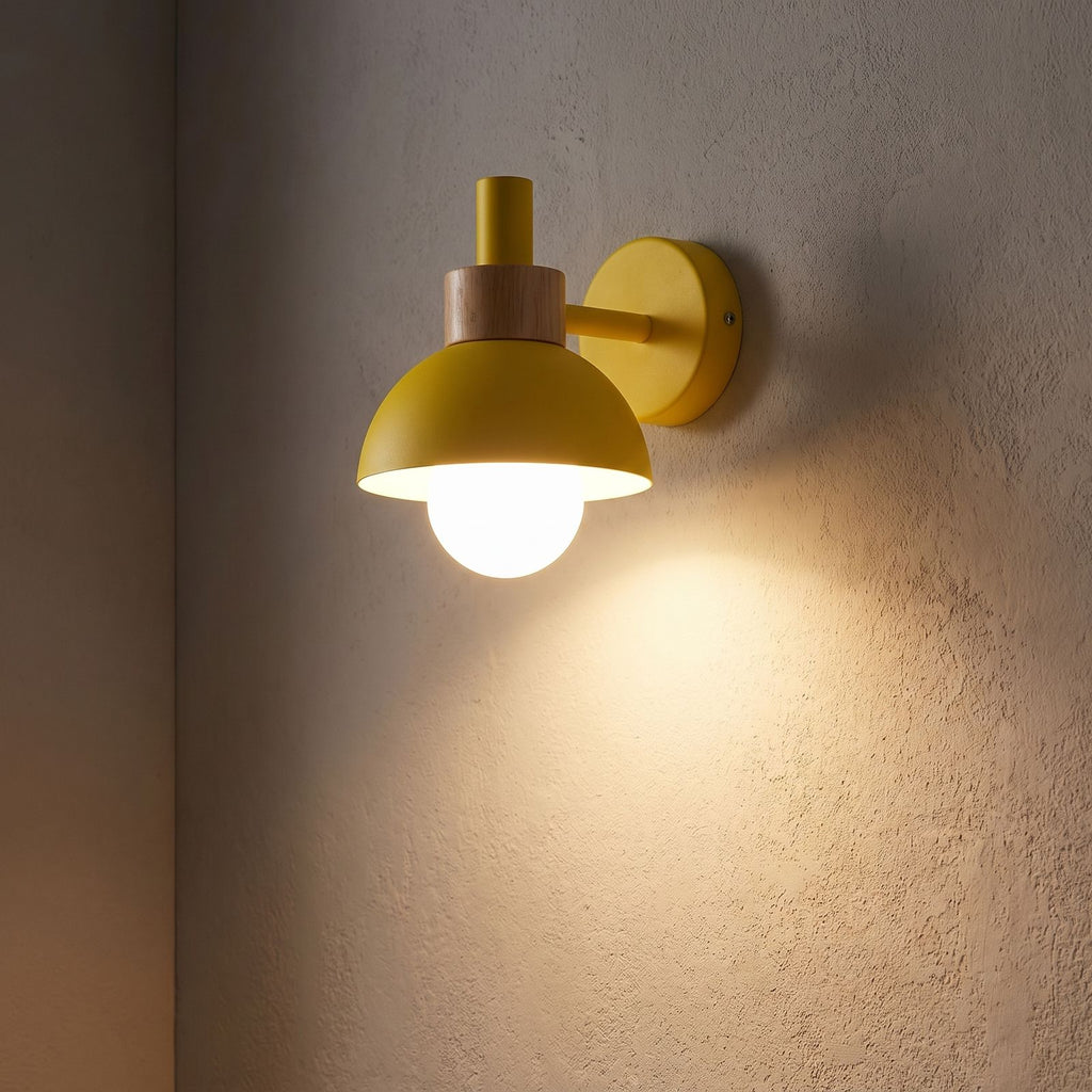 Coloured Matte Iron Cylinder Wall Light glowing on a plaster wall at night