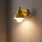 Coloured Matte Iron Cylinder Wall Light glowing on a plaster wall at night