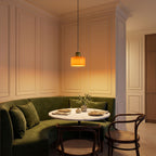 Colourful Two-Tone Glass Drum Pendant Light in orange glass with a green cap above a round bistro table in a classic dining nook in the evening