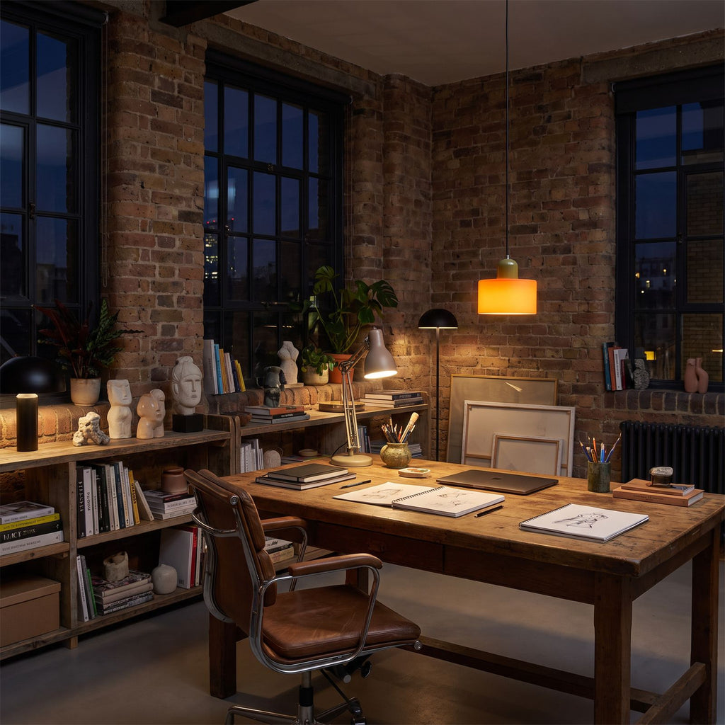 Colourful Two-Tone Glass Drum Pendant Light in orange glass above a timber desk in a home office studio at night
