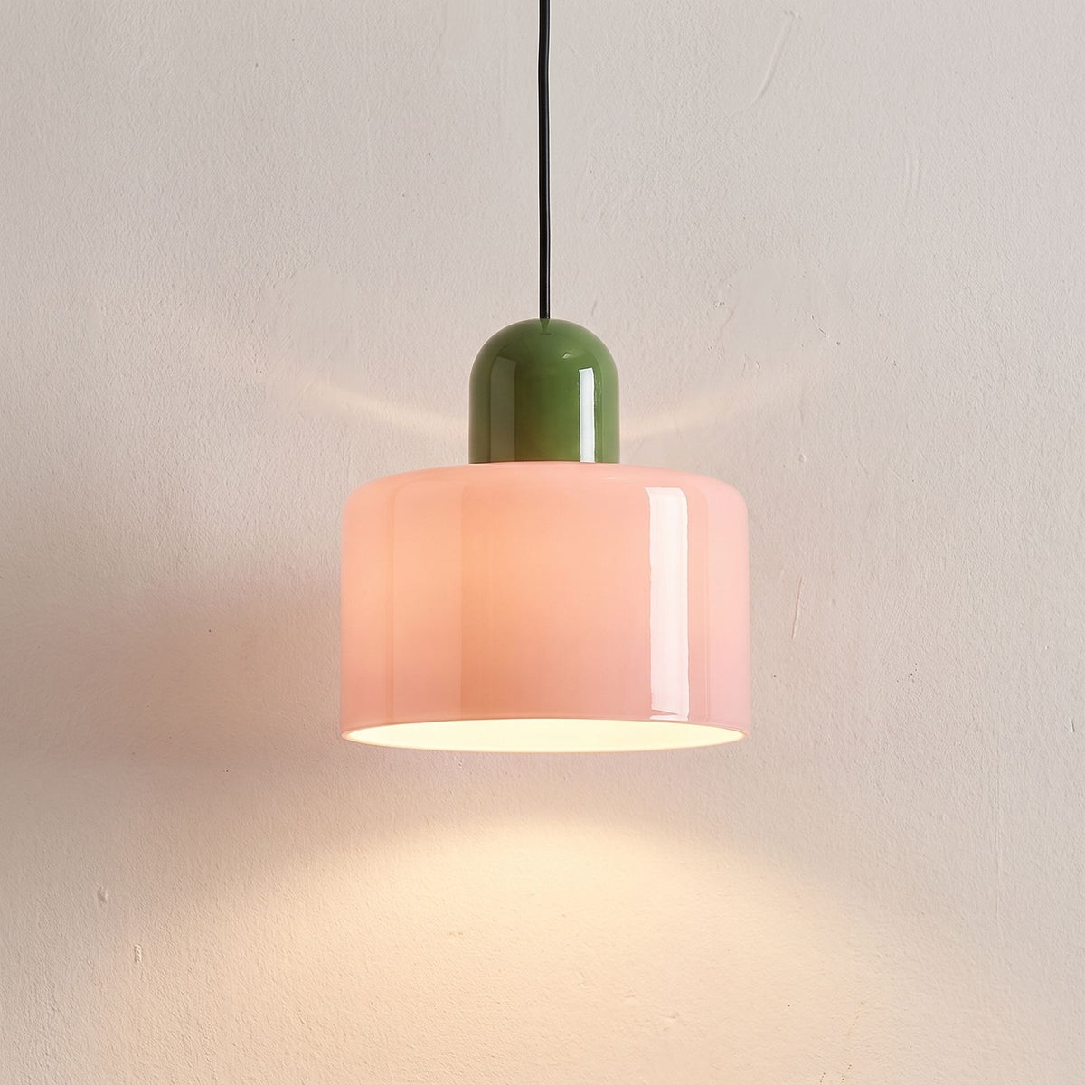 Colourful Two-Tone Glass Drum Pendant Light in pink glass with a green cap, close view of the glossy glass drum switched on