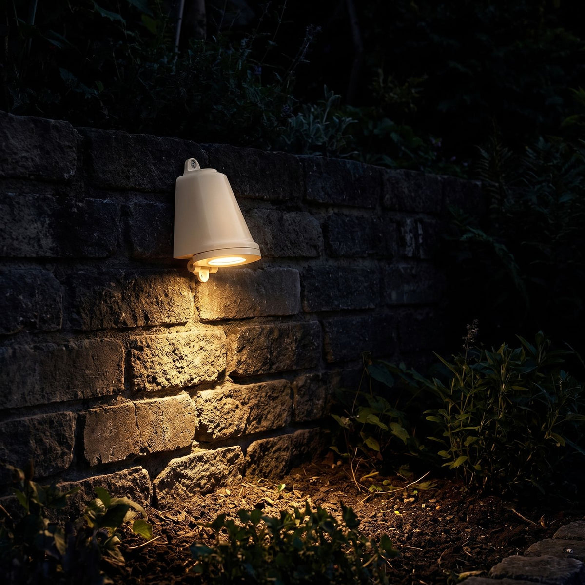 Compact Aluminium LED Outdoor Wall Light glowing on a garden wall at night