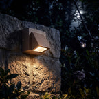 Compact Metal LED Outdoor Wall Light glowing on a garden wall at night