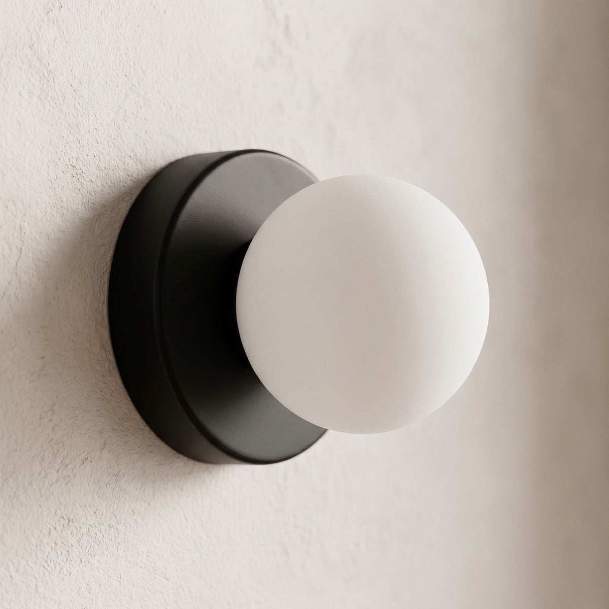 Compact Rounded Glass and Iron Wall Light, close view at 45 degrees on a plaster wall