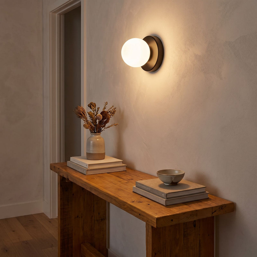 Compact Rounded Glass and Iron Wall Light in a hallway above a timber console