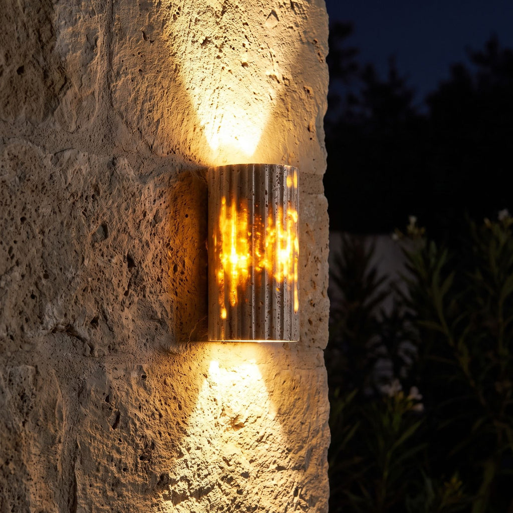 Compact Yellow Travertine Up Down Outdoor Wall Light glowing on a garden wall at night